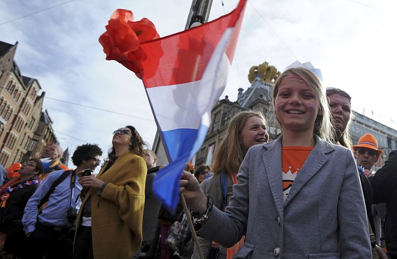 A woman waves a flag as she waits for Queen Beatrix's abdication ceremony in Amsterdam