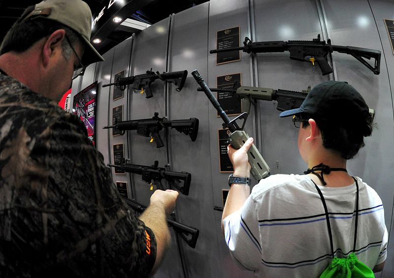 Un padre acude junto a su hijo a la convención de la Asociación del Rifle