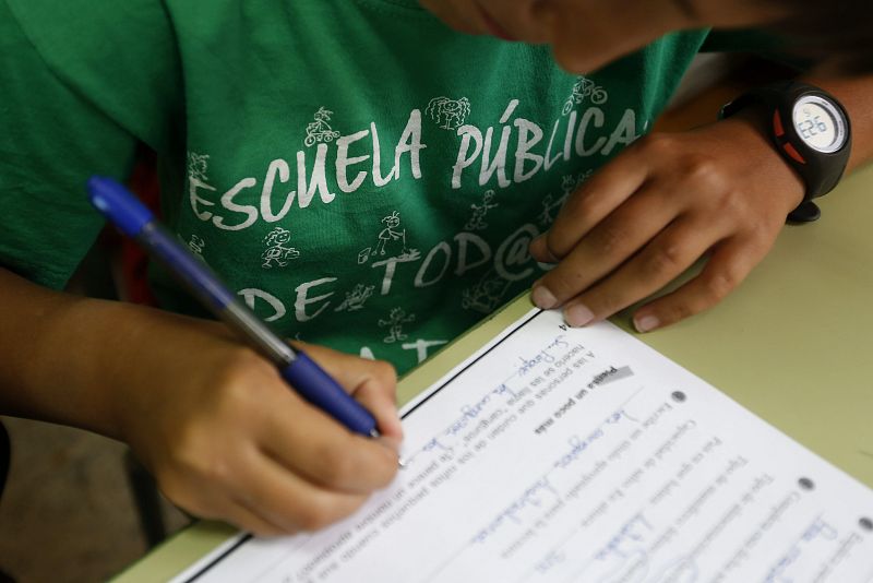 Un alumno del Colegio Joaquín Costa de Madrid rellena una ficha con la camiseta a favor de la escuela pública