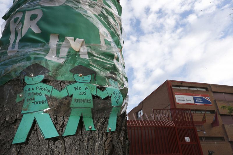 Detalle de un árbol en el exterior del Colegio Joaquín Costa de Madrid con carteles contra los recortes