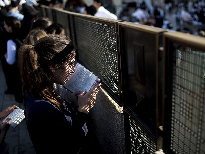 Una mujer reza frente a la valla de separación entre sexos en la explanada del Muro.