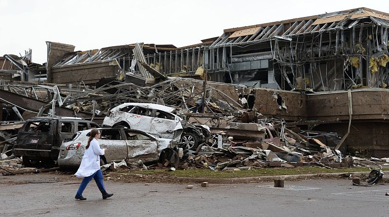 Una enfermera camina frente a coches y edificios derrumbados por el tornado gigante que ha asolado la zona sur de Oklahoma City, en Estados Unidos