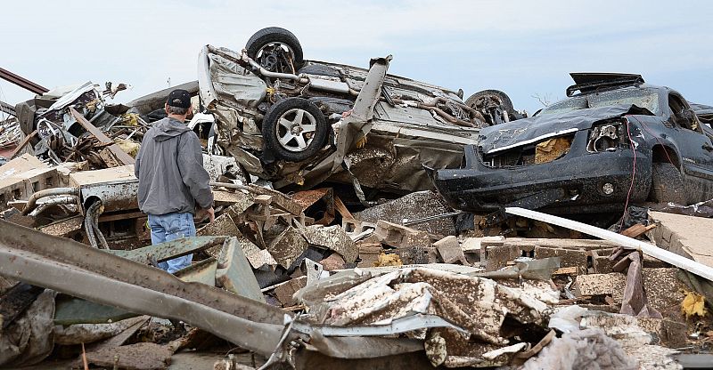 Un hombre observa los coches arrastrados por el tornado sobre los escombros de varios edificios en Oklahoma