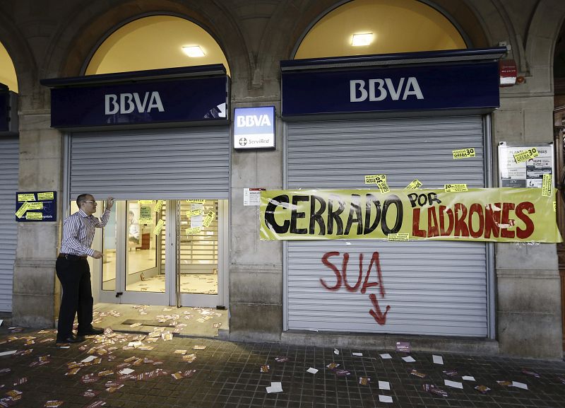 Un trabajador cierra una sucursal bancaria de BBVA en Pamplona, tras las protestas