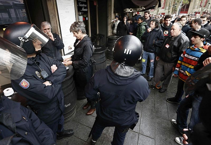 Efectivos de la Policía Nacional protegen a varios turistas en el exterior de un bar abierto