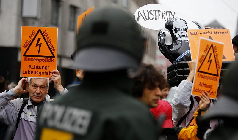 Demonstrators hold signs in front of riot police near the ECB headquarters during an anti-capitalist "Blockupy" demonstration in Frankfurt