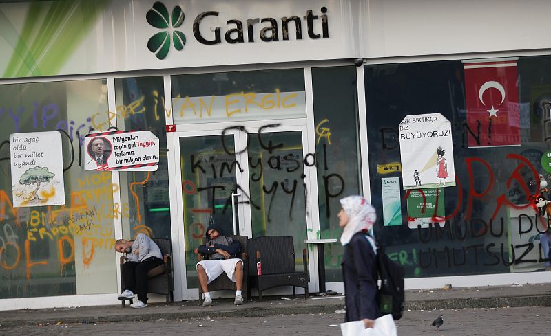 Tras una noche de disturbios, dos manifestantes descansan ante una sucursal de Garanti Bank en Estambul.