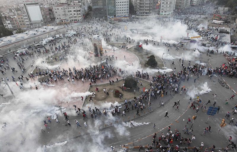 Protesters run as riot police fire teargas during a protest at Taksim Square