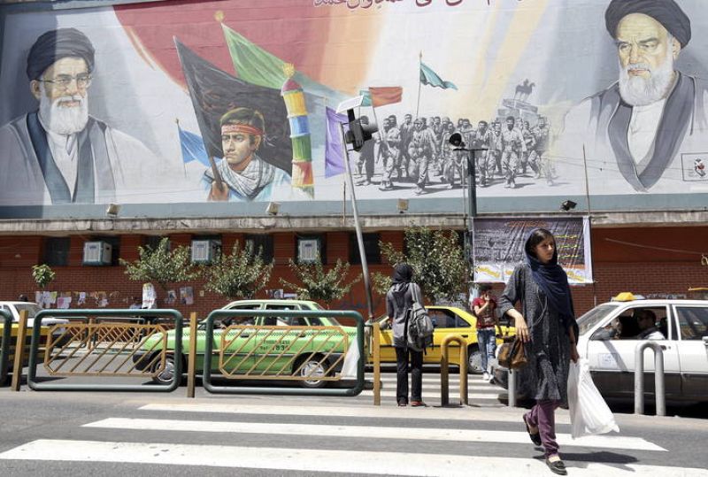 Ciudadanos iraníes caminan junto a un cartel que representa al líder supremo de Irán, ayatolá Ali Jamenei, (izda), junto al fallecido  ayatolá Ruhola Jomeini 