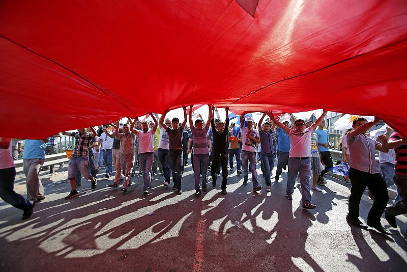 Supporters of PM Erdogan march holding a huge Turkish flag during a rally of ruling AK party in Istanbul