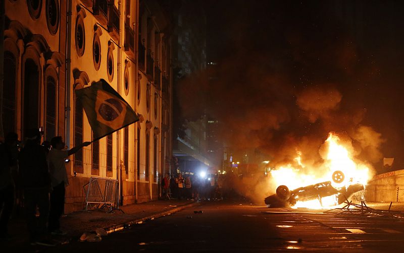 Un coche arde en las calles de Rio de Janeiro, frente a la Asamblea Legislativa, que ha sido tomada temporalmente por unos manifestantes que han subido a los tejados y roto algunos ventanales