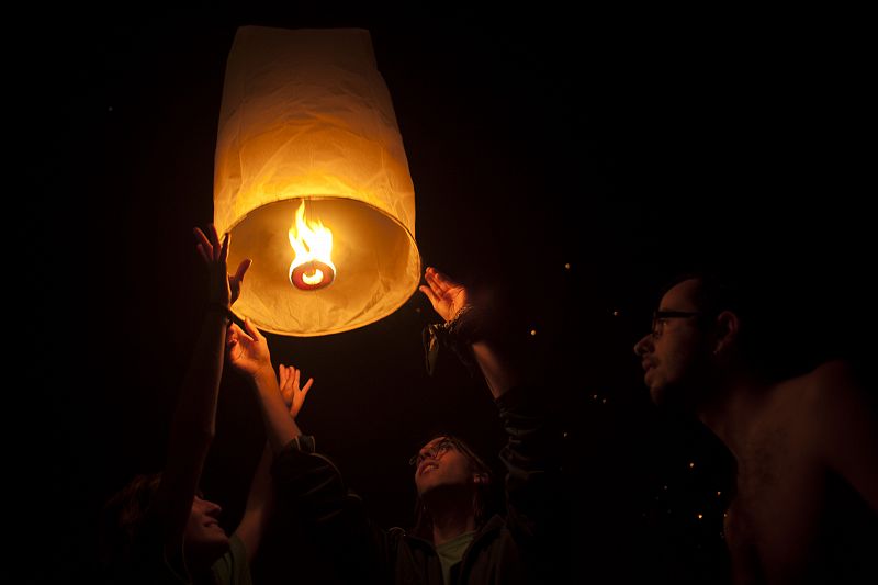 Gente lanzando un farolillo al aire en la noche de San Juán de Málaga