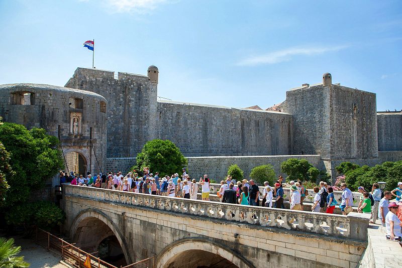 Una multitud de turistas cruza un puente en el casco histórico de la ciudad de Dubrovnik.El turismo domina el sector servicios en Croacia y provee más del 20% de su PIB