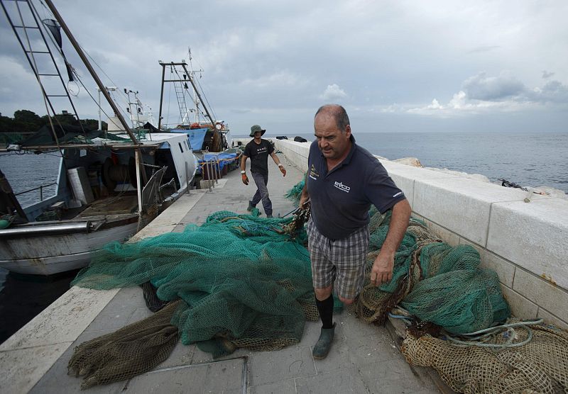 Un pescador quita una red de pesca de su barco en el puerto de la ciudad de Savudrija. Los pescadores croatas deberán acogerse a las estrictas leyes y regulaciones de la Política Común de Pesca de la UE.