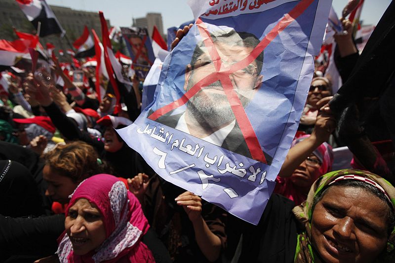 Protesters holding poster opposing Egyptian President Mursi shout slogans against him and brotherhood members during protest at Tahrir square in Cairo