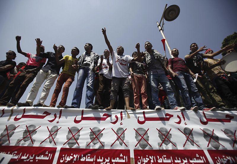 Protesters opposing Egyptian President Mursi shout slogans on banner with pictures of Brotherhood members during protest in front of El-Thadiya presidential palace in Cairo