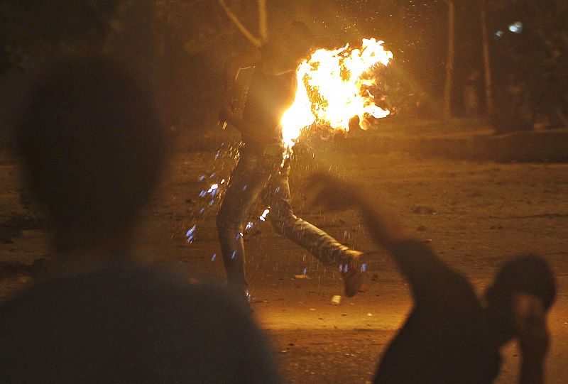 Uno de los asaltantes corre tras coger fuego por uno de los cócteles molotov que iba a lanzar