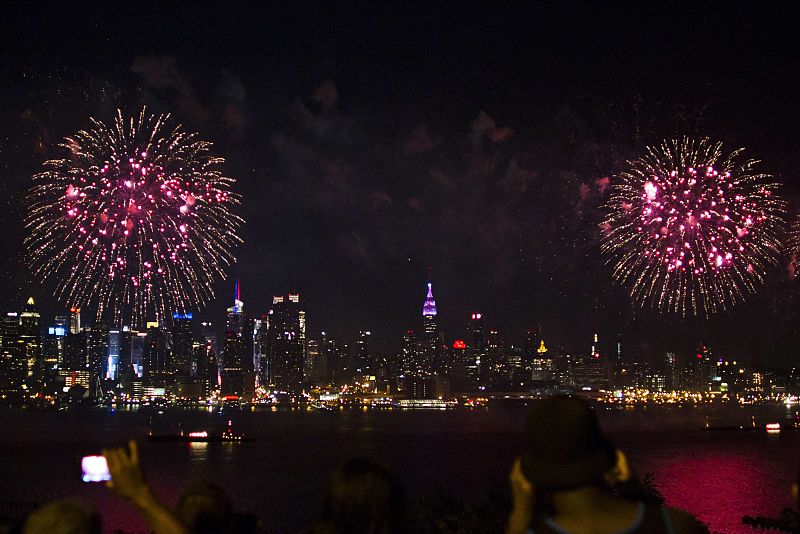 La gente observa los fuegos artificiales sobre el río Hudson, con el horizonte de Nueva York alfondo, durante la celebración del Día de la Independencia