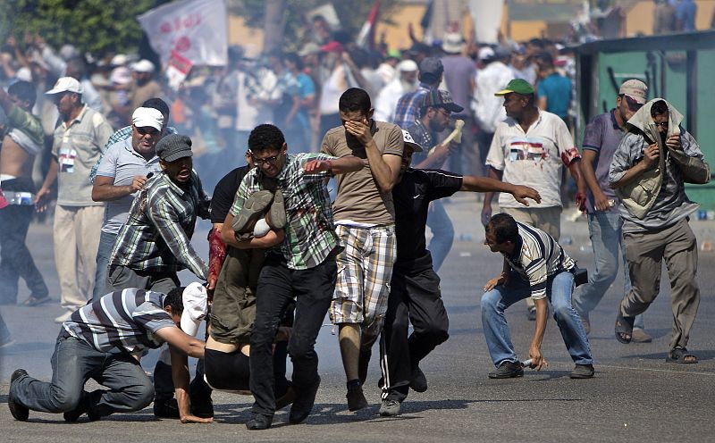 Partidarios de Morsi evacuan a un herido en los enfrentamientos en las inmediaciones de la se de Guardia Republicana.