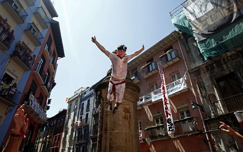 Un joven salta desde la fuente de la Navarrería de Pamplona, tras el lanzamiento del chupinazo