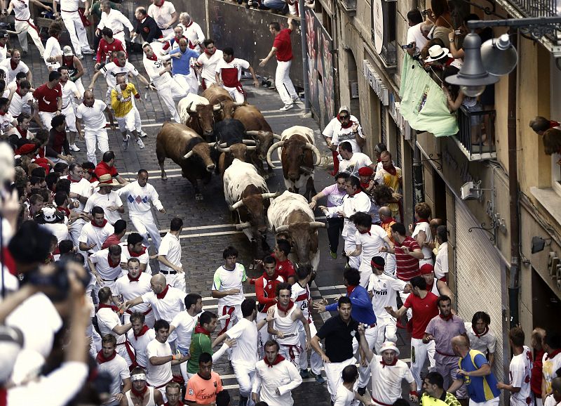 Los mozos corren, en el inicio de la calle Estafeta, delante de los toros de la ganadería toledana de Alcurrucén.