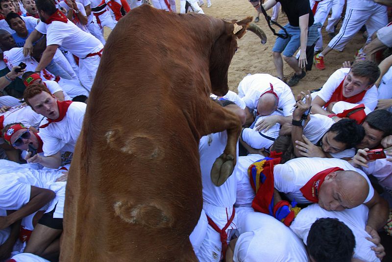 A fighting cow leaps over revellers following the first running of the bulls of the San Fermin festival in Pamplona