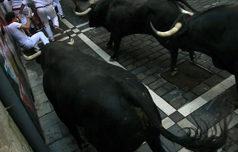 Runners fall in the path of Dolores Aguirre Ybarra at the Estafeta corner during the second running of the bulls of the San Fermin festival in Pamplona