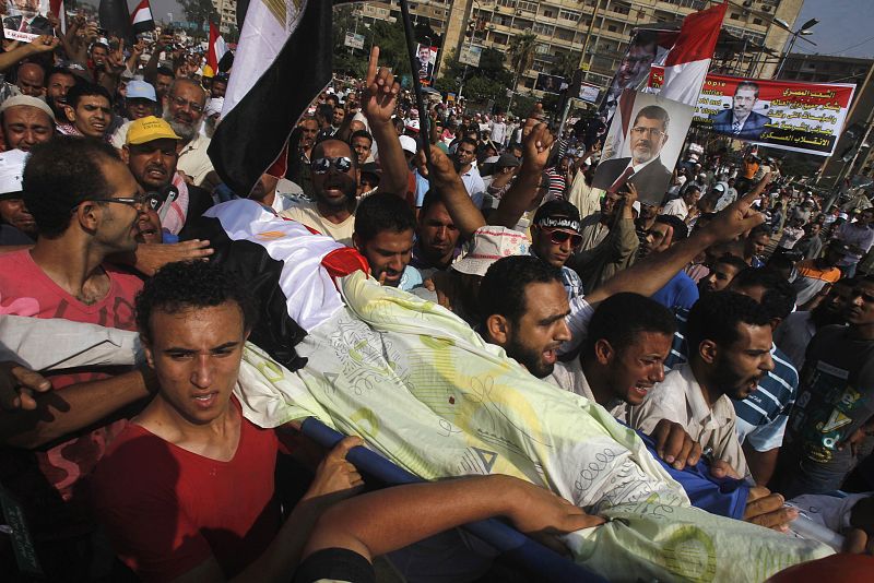 Supporters of Mursi carry the body of a fellow supporter killed by violence outside the Republican Guard headquarters in Cairo