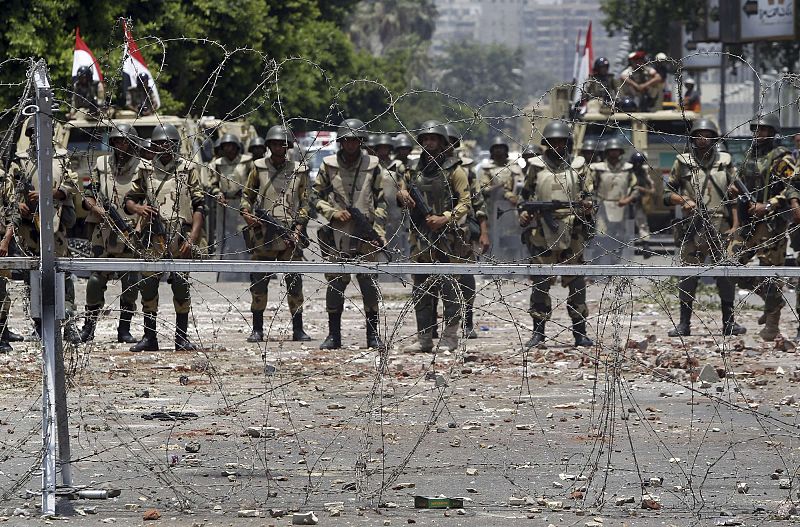 Army soldiers stand guard at Republication Guard headquarters after early clashes in Nasr City