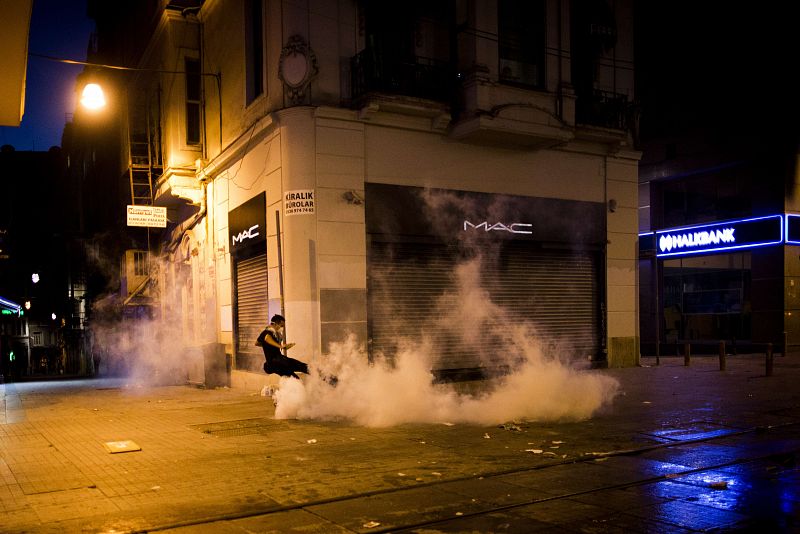 Un manifestante aparta de una patada un bote de gas lacrimógeno en mitad de una humareda y en las calles que rodean el parque Gezi de Estambul.