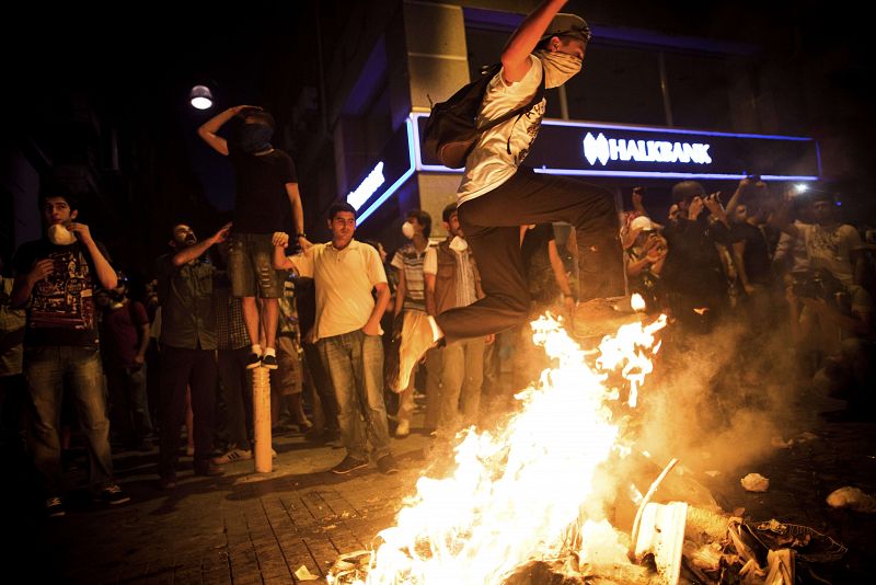 Uno de los manifestantes turcos salta una hoguera durante una protesta en la avenida Istiklal en Estambul. La policía antidisturbios ha disparado balas de goma, gases lacrimógenos y cañones de agua para impedir que los manifestantes entraran en el pa