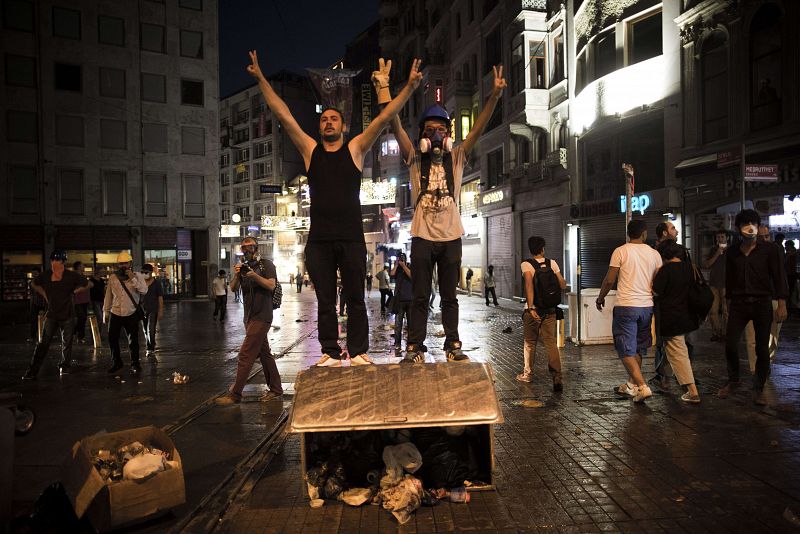 Manifestantes turcos gesticulan el símbolo "V" de la victoria subidos a un contenedor de basura derribasddo durante la protesta en avenida Istiklal en Estambul.