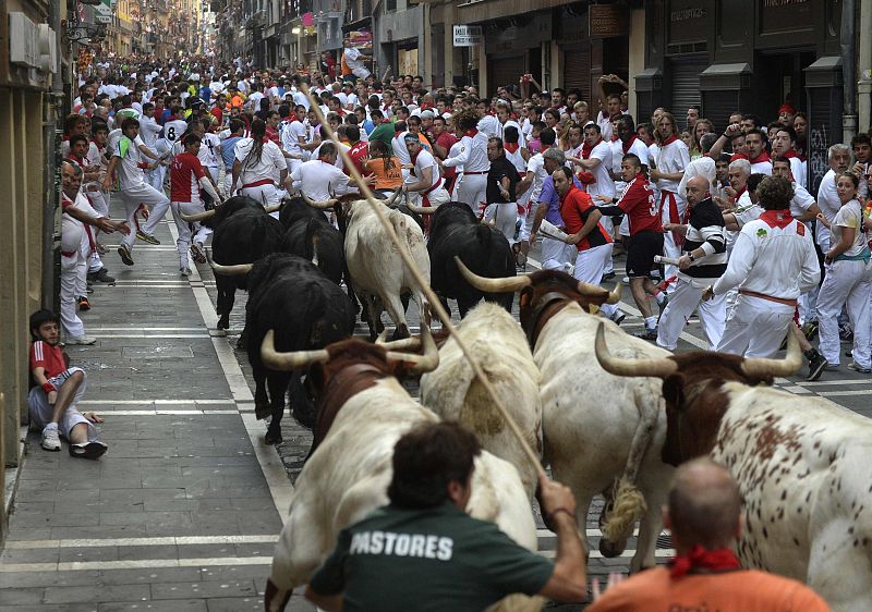 A fallen runner watches Valdefresno fighting bulls on Estafeta Street during the third running of the bulls of the San Fermin festival in Pamplona