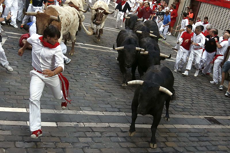 Un joven corre delante de los astados de Victoriano del Río a la altura de Estafeta en el cuarto encierro de los Sanfermines 2013