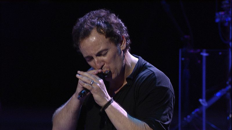 Primer plano de Bruce en un concierto tocando la armónica