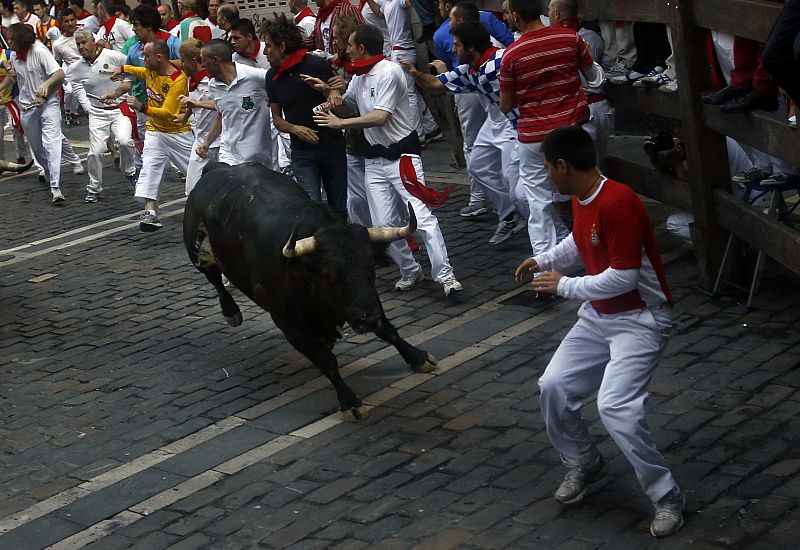 Un mozo encara a un toro de Torrestrella en la curva de Estafeta