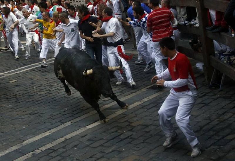 Un mozo encara a un toro de Torrestrella en la curva de Estafeta