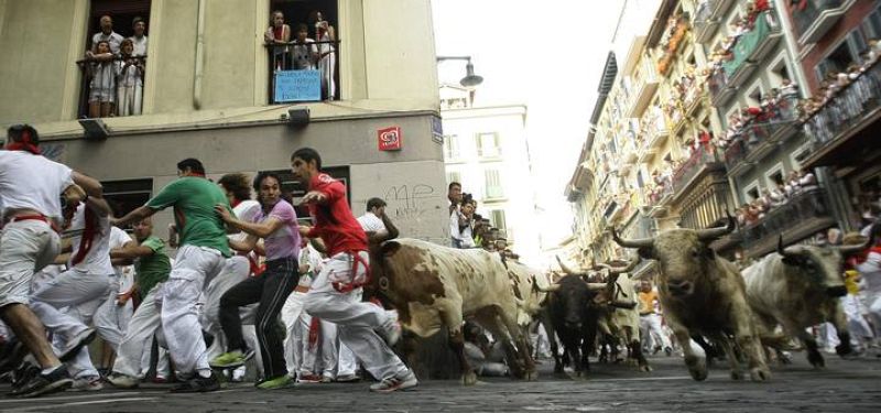 Los mozos toman la curva de Estafeta delante de los toros de Torrestrella durante el quinto encierro de San Fermín 2013