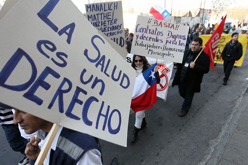 Los manifestantes alzan pancartas con mensajes que reclaman salud pública y un salario digno durante la huelga general en Santiago, Chile