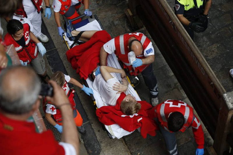 Las asistencias sanitarias auxilian a un joven  tras un enganchón durante el sexto encierro de los sanfermines donde los toros de la ganadería de El Pilar (Salamanca) han protagonizado un peligrosísimo y largo sexto encierro