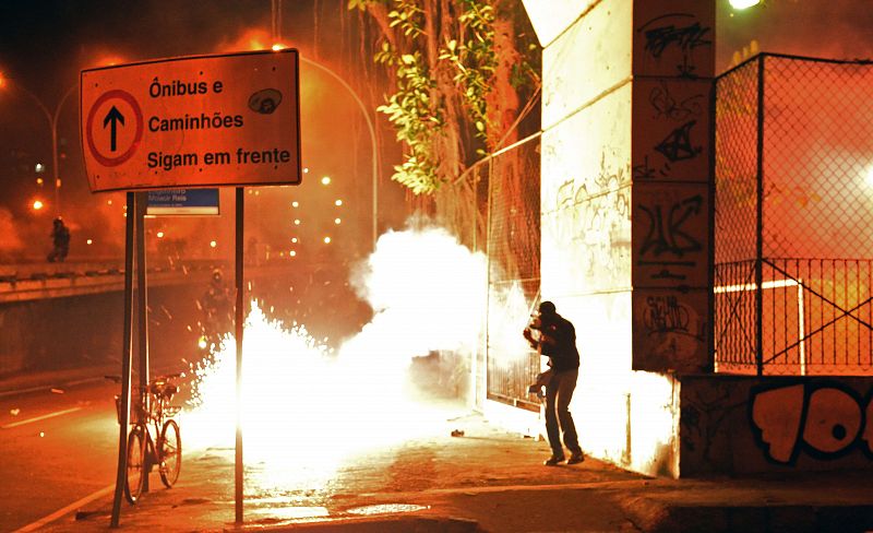 Los policías antidisturbios se protegen de cócteles molotov lanzados por manifestantes violentos en Río de Janeiro, Brasil, con motivo de las protestas por la visita del papa