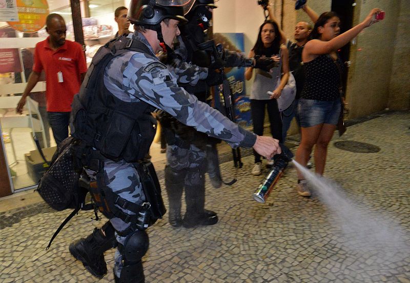 Un policía emplea gases lacrimógenos para disolver a los manifestantes que han protestado en Río de Janeiro contra la visita del papa con motivo de la JMJ