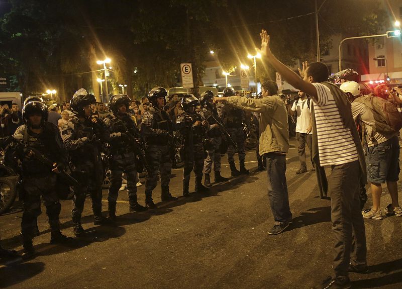 Varios manifestantes se enfrentan a la policía antidisturbios con los brazos en alto, frente al palacio presidencial Guanabara, en Río de Janeiro, donde la presidenta Dilma Rousseff recibía en un acto de bienvenida al papa Francisco