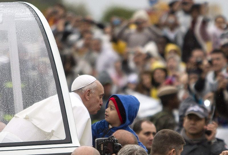 El papa Francisco besa a un niño durante su recorrido, que ha realizado en papamóvil.