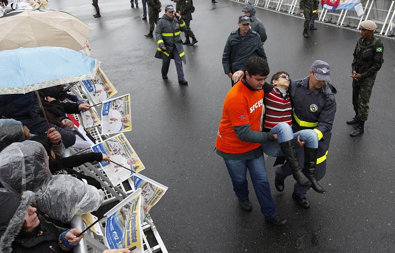 Los voluntarios ayudan a una fiel desmayada mientras esperaba al papa Francisco en el santuario de la Virgen de Aparecida.
