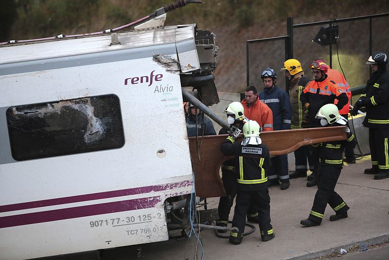 Los bomberos inspeccionan el interior de uno de los vagones siniestrados en el accidente de tren.