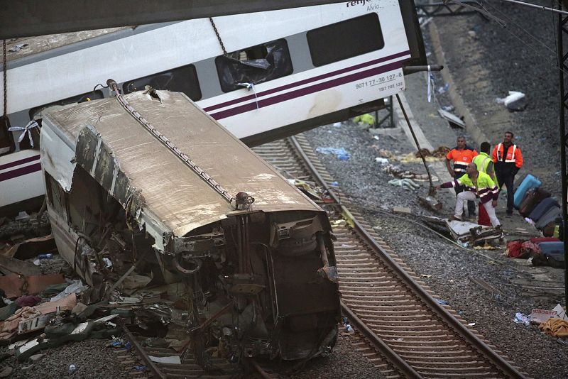 Los equipos de rescate retiran fragmentos del tren siniestrado y equipaje de las vías cerca de Santiago de Compostela.