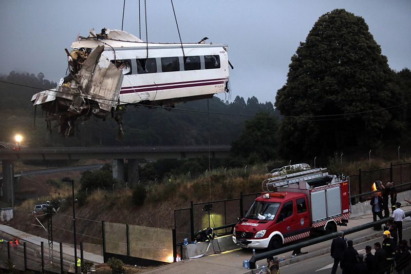 A crane removes a carriage from the tracks at the site of a train crash near Santiago de Compostela
