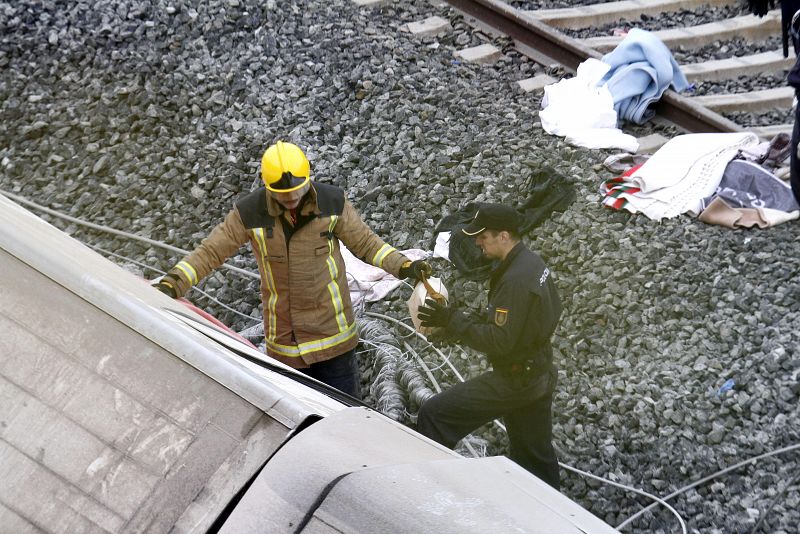 Un bombero entrega un bolso a un agente de la policía que acaba de extraer de uno de los vagones del tren accidentado.