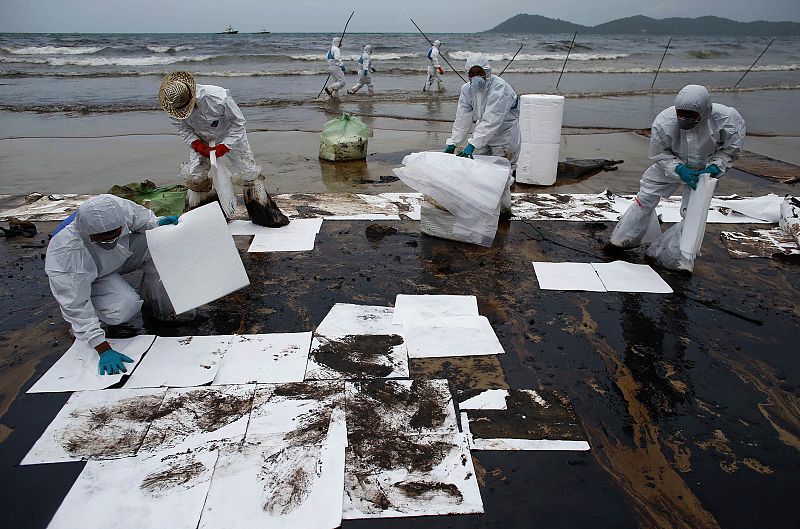 Los soldados colocan láminas de un papel especial para limpiar las playas del vertido de petróleo de la empresa PTT Global Chemical Pcl que afecta el este de Tailandia.